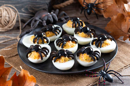 The idea for decorating a table for Halloween: stuffed eggs with spiders from olives, horizontalの写真素材