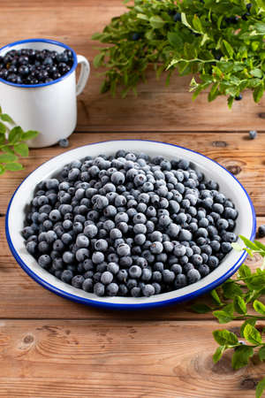 Frozen blueberries in a metal bowl on rustic wooden tableの写真素材