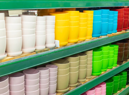 Empty flower pots in a store or greenhouse. Ceramic or plastic flower pots at the shop. Colorful flower pots on the shelf in the store. Colorful pots for plants.の写真素材