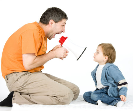 A studio view of a man with a hand-held, electronic megaphone or bullhorn, yelling at a small boy holding fingers in his ears.の写真素材