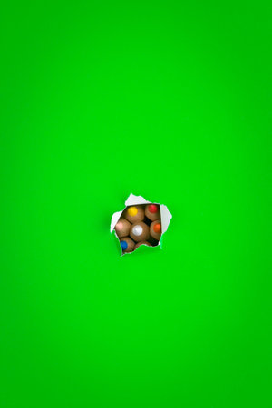 A green background with colored pencils pushing through.の写真素材