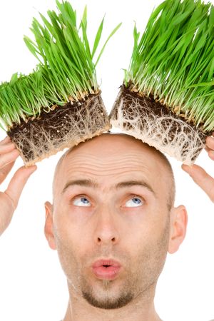 Blue eyed hairless man with beard on white background look on green grass on his headの写真素材
