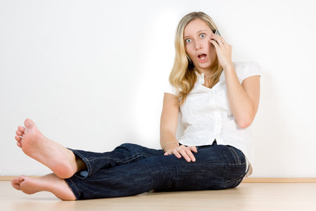 A metaphorical image of a girl with a shocked expression on her face, while talking on the phone.の写真素材