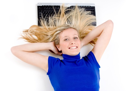 A young blond woman relaxing near her computer at her office, on white studio background.の写真素材