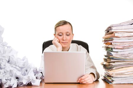 Thinking or tired businesswoman with stack of paperwork, pile of crumpled papers and a laptop computer.の写真素材