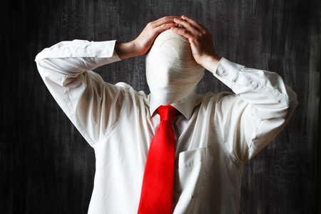Half body portrait of businessman with face obscured by bandages, dark background.の写真素材