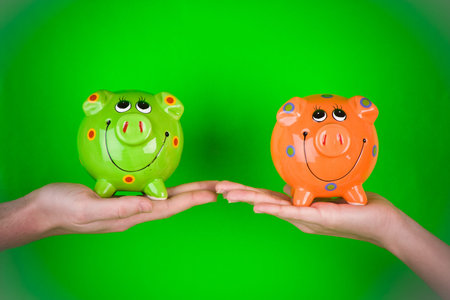 A pair of hands holding ceramic piggy banks.の写真素材