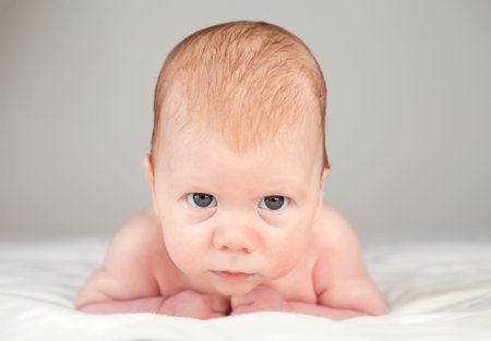 Very young baby boy holding his head up and looking straight ahead.
