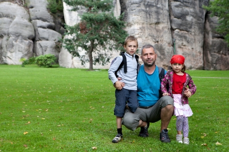 Father and children pose for family photograph beside extensive rock face. の写真素材