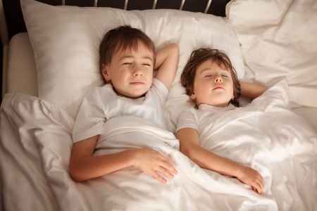 Cute young preschool brother and sister sleeping together in bed.の写真素材