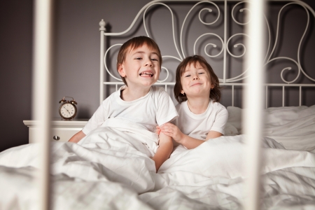 Brother and Sister in their parents bed pulling funny faces. の写真素材