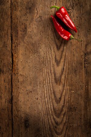 Two ripe red chili peppers on dark wooden background with copy space.の写真素材