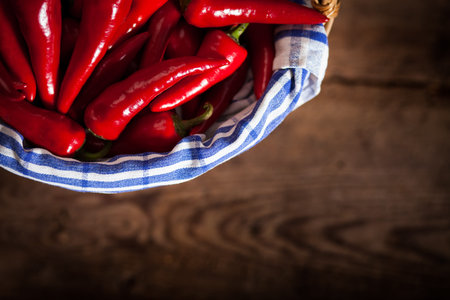 Cayenne chili peppers in a basket with a blue cloth on wood.の写真素材