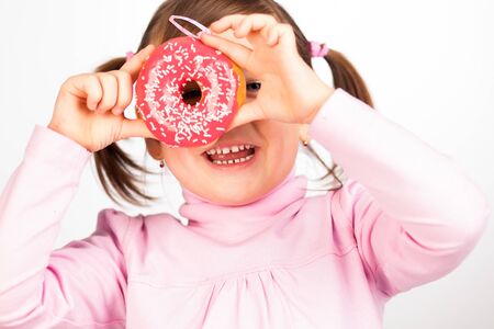 Portrait of young girl looking through two pink donuts, white backgroundの写真素材