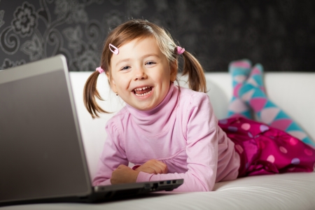 Young girl uses a laptop computer at home.の写真素材