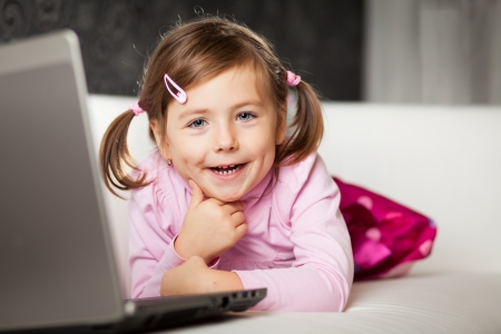 Young girl uses a laptop computer at home.の写真素材
