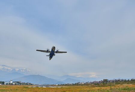 Pokhara, Nepal - April 13, 2019: An airplane of local Nepalese airlines flying against the mountain...