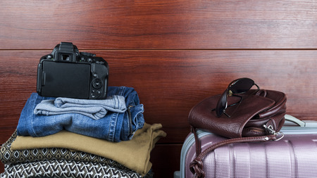 Women's things lie at the closet with things with suitcase and women's bag and camera the concept of preparing for a tripの写真素材