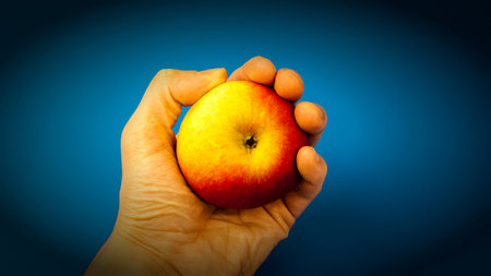 A man's hand holds an apple
