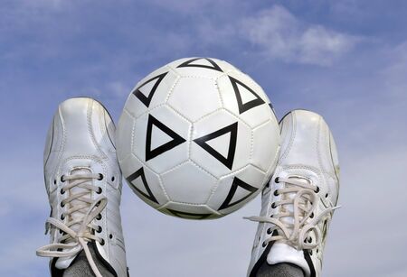 soccer ball between the legs on the background of the skyの写真素材