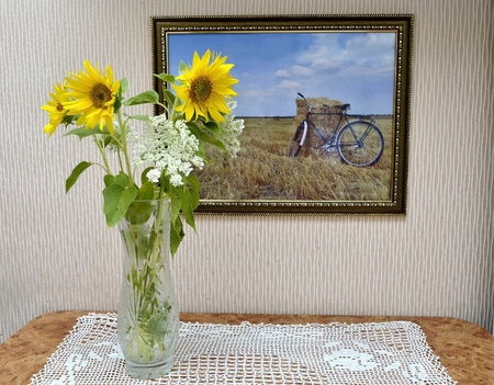 Sunflowers stand in a vase on the table and the pictureの写真素材