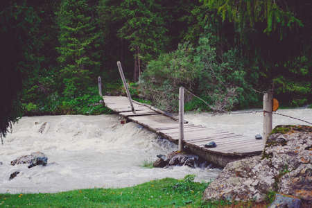 Bridge over the rough mountain river clouds, streamの写真素材