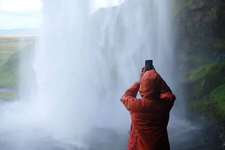 Tourist photographs a waterfallの写真素材