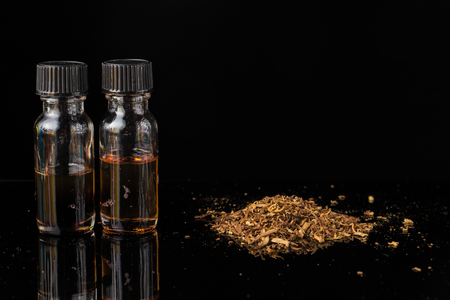 E-liquids next to pile of grinded tobacco leavesの写真素材