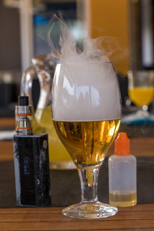 Vaporizer and smoking beer with bottle on tableの写真素材