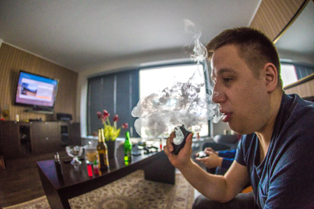Young man exhaling vapor from electronic cigaretteの写真素材