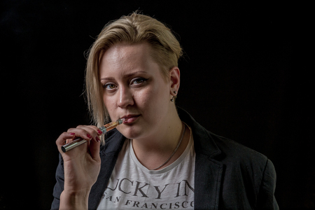 Woman holding electronic cigarette between her teethの写真素材