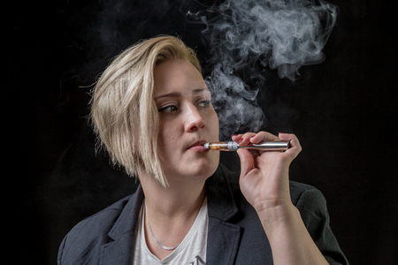 Woman looking on the side while smoking electronic cigaretteの写真素材
