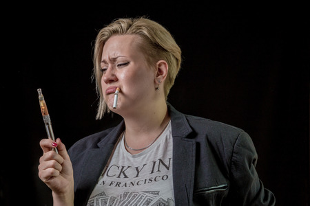 Woman looking at electronic cigarette and is doubtingの写真素材