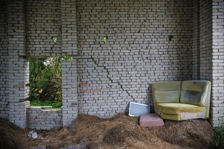 Decayed sofa on hay in abandoned houseの写真素材