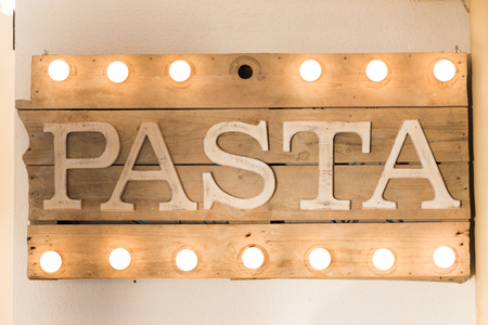 Pasta sign made of wooden planks and light bulbs on top and bottomの写真素材