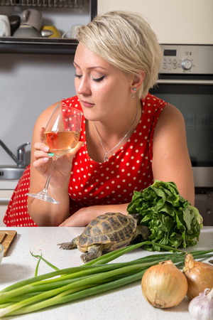 Girl looking  at wine glass while tortoise eats saladの写真素材