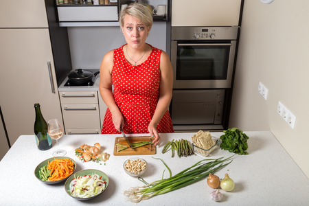 Surprised young woman in kitchen cutting asparagusの写真素材