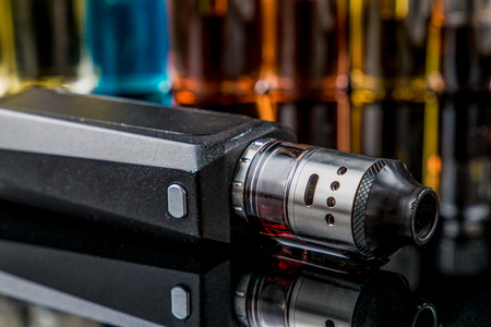 Electronic cigarette on the side with e-juice bottles in the backgroundの写真素材