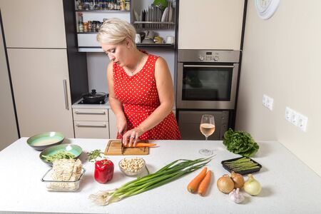 Girl cutting carrot and preparing for vegetable wokの写真素材