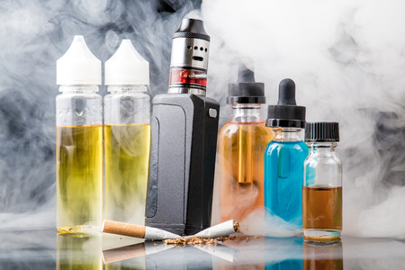 Modern vaporiser versus old tobacco cigarette in smoke cloudの写真素材