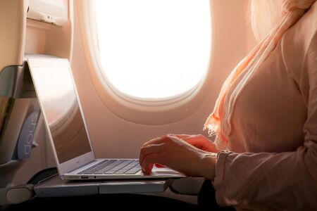 Woman using computer on airplaneの写真素材
