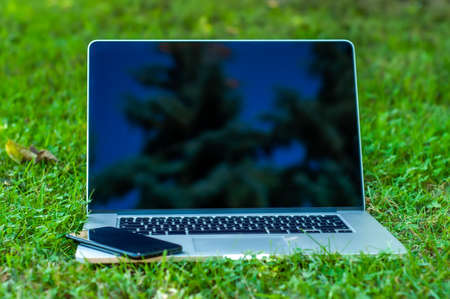 View on a laptop pc and a smartphone on the grass in the garden in a home office or home school enviroment on a sunny day.の写真素材