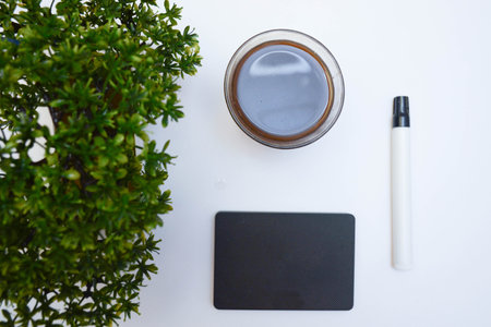 Office desk table with coffee cup, notebook, pen and plant.