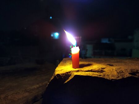 A CANDLE FLAME GIVE LIGHT IN DARK NIGHT WITH BLINKING LIGHTS