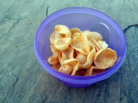 some yellow eatable food put in blue plastic bowl on stone background