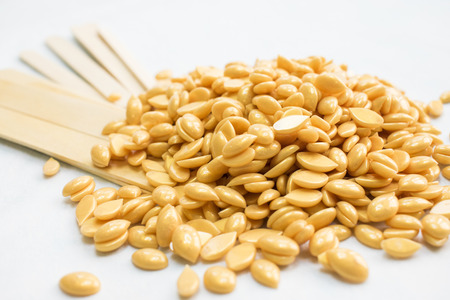 on a white background isolated there are granules of a gold wax and wands for depilation.の写真素材