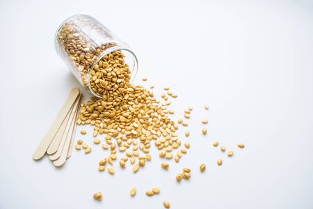 Isolated on a white background is a glass jar with golden wax and wooden sticks for depilation.の写真素材