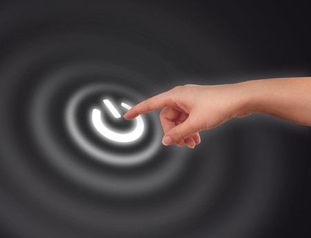 The hand presses On/Off button on black backroundの写真素材