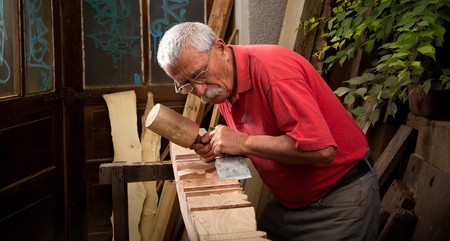 Old woodcarver working with mallet and chiselの写真素材