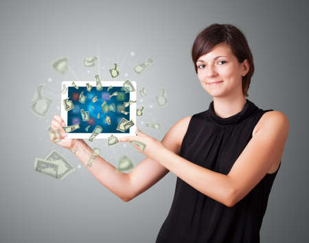 beautiful young woman holding tablet with moneyの写真素材